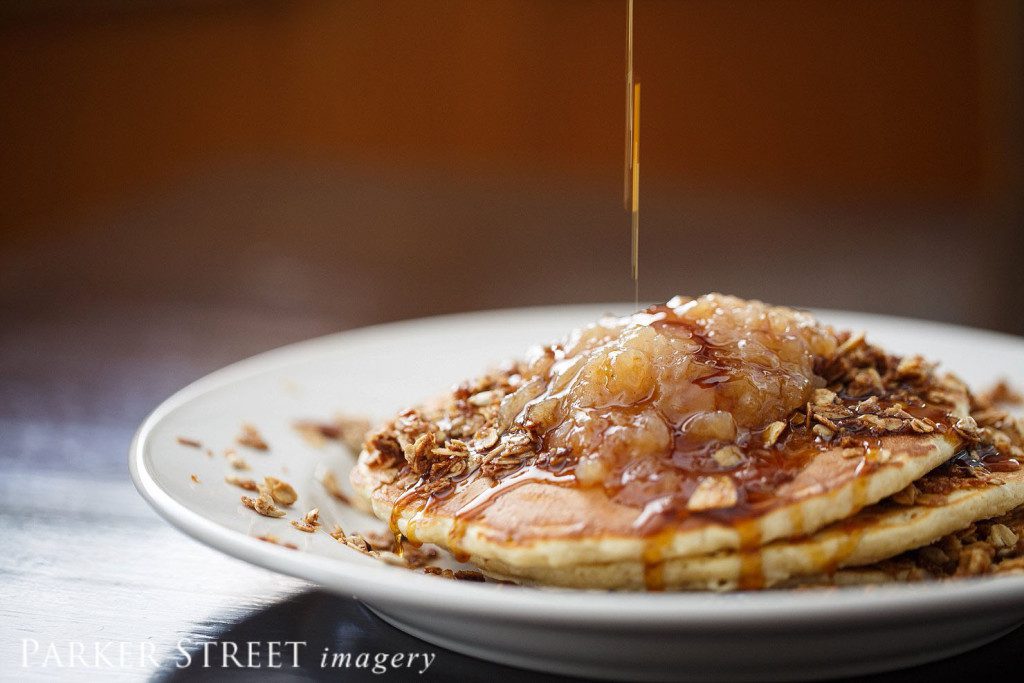 Professional photo of Apple Granola Pancakes with maple syrup drizzle | Black Forest Cafe | Amherst, NH